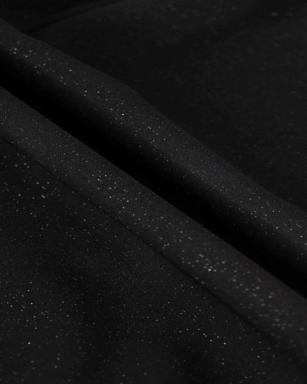 A fine scattered glimmer becomes visible across the dark fabric where it folds.