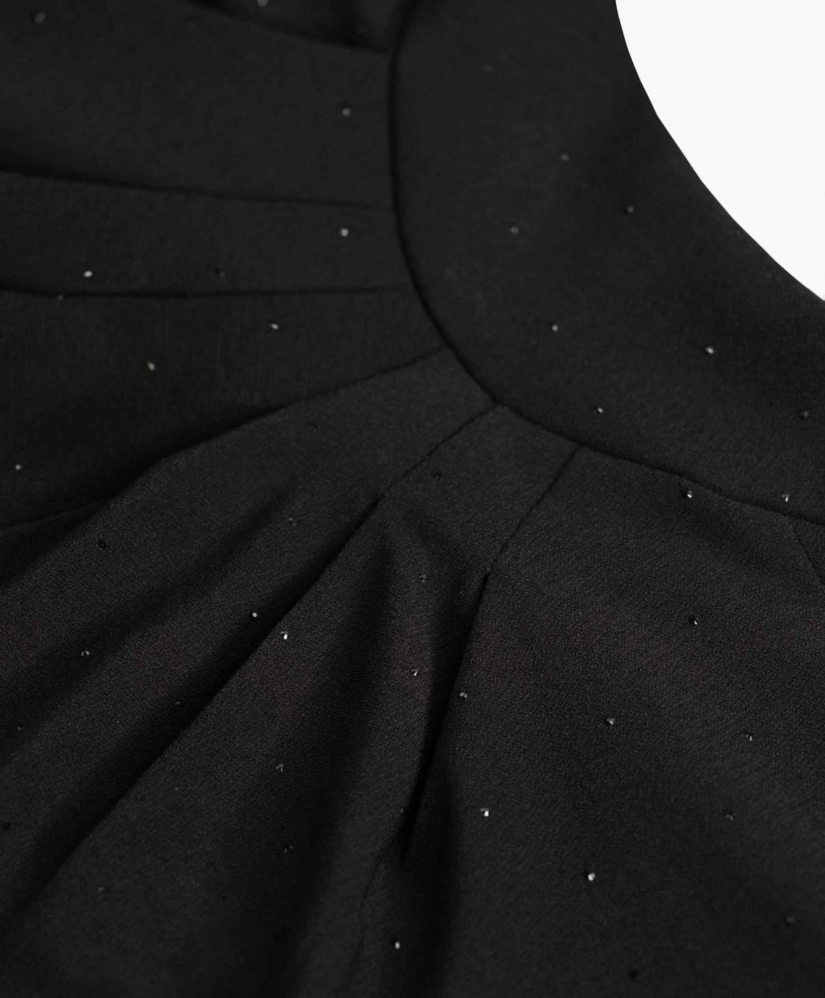 Fine pleats radiate beneath the curved upper edge, with small reflective points scattered across the dark surface.