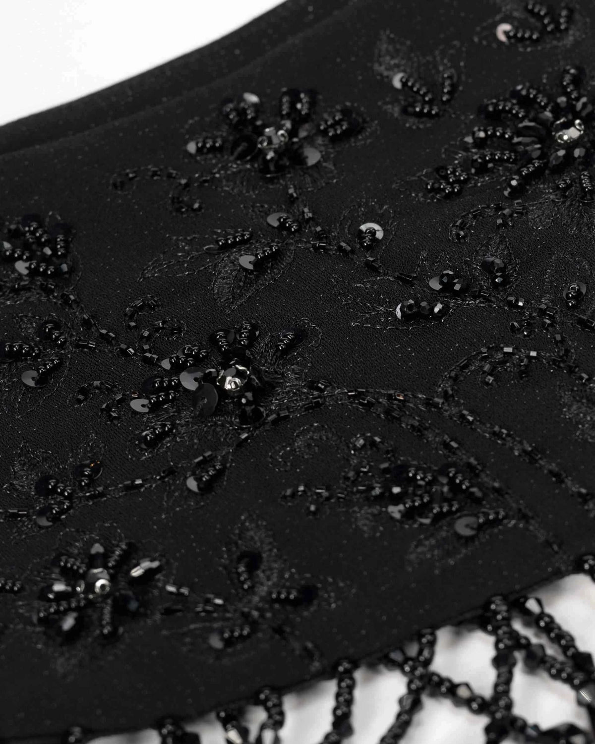 Dark decorative clusters form small floral shapes across the shawl, catching light in scattered points.