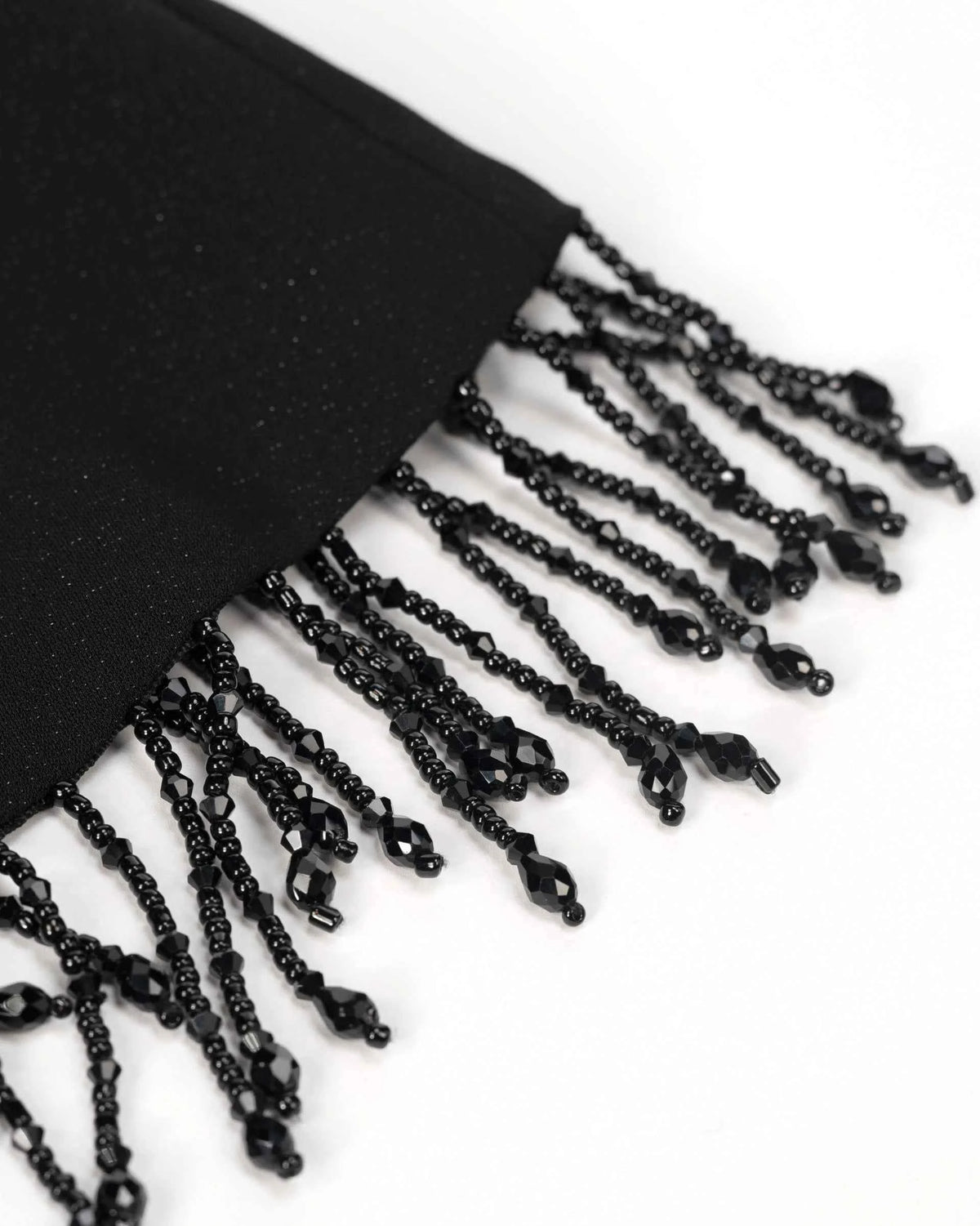 A row of dark strands falls from the shawl's lower edge, with small decorative ends visible close up.