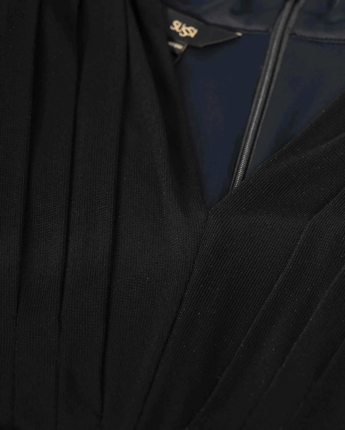 Long folds follow the deep neckline and lead down towards the waist.