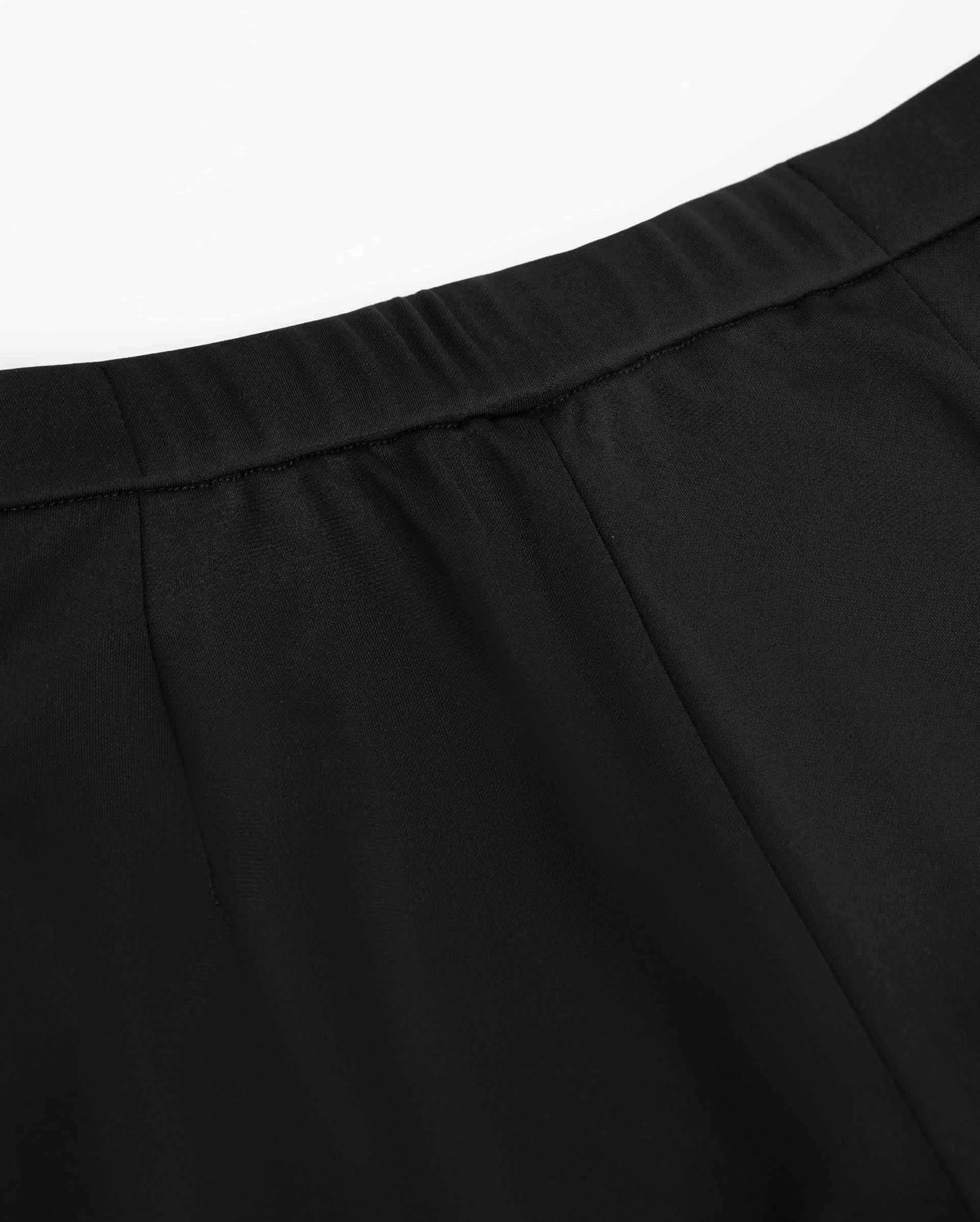 The back waistband reveals closely spaced gathers above the smooth dark fabric.