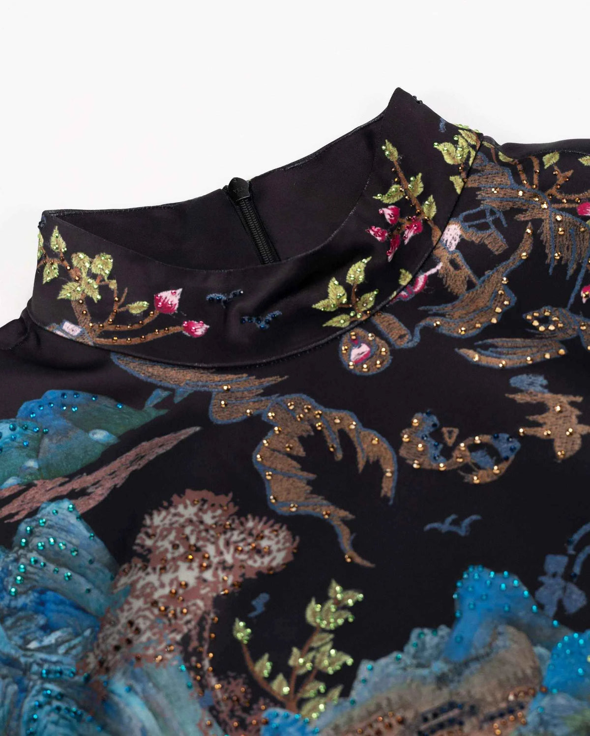 Colourful scenic embroidery continues into the upright collar, connecting the upper edge with the detailed shawl below.