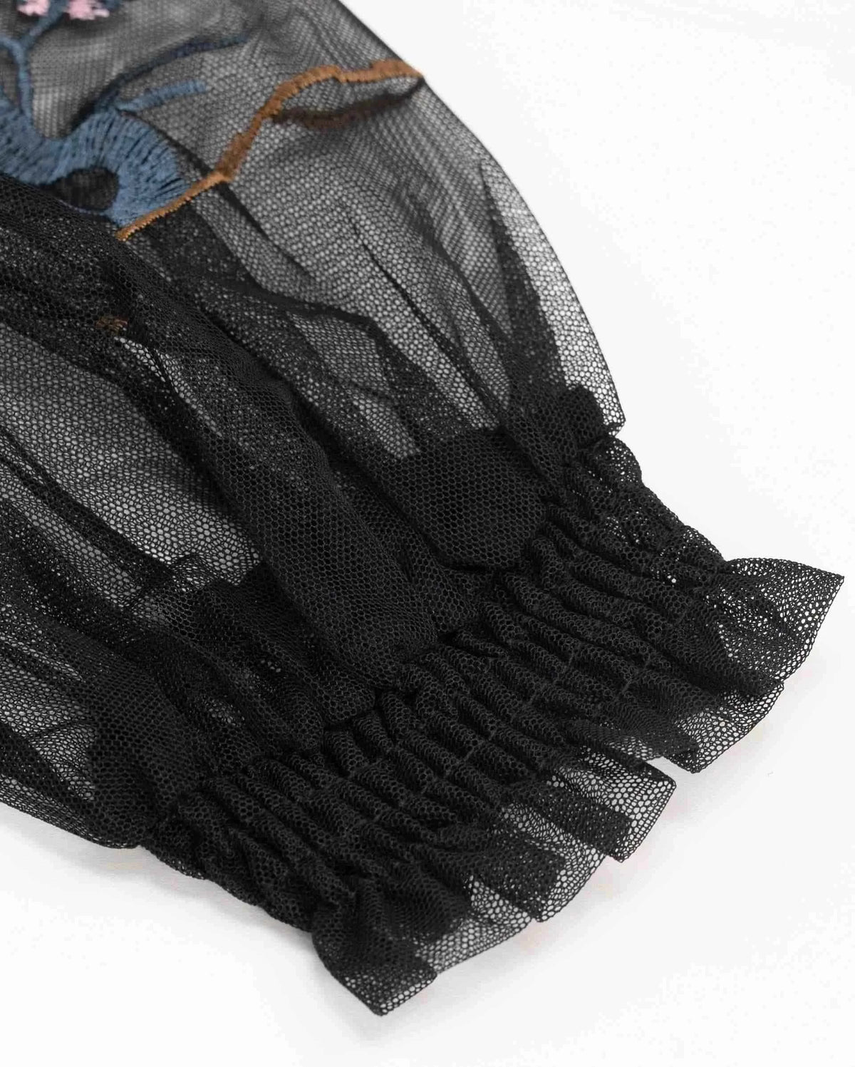 The transparent sleeve gathers into a closely textured dark cuff beneath the embroidered detail.