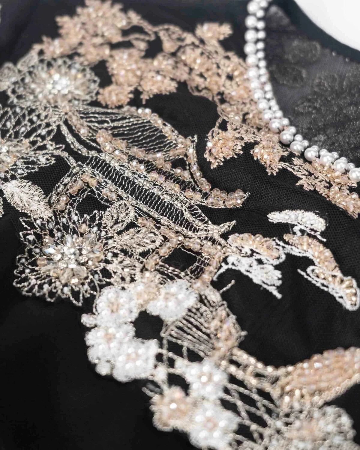Pale flowers and architectural details fill the transparent upper section, with fine outlines visible against black.