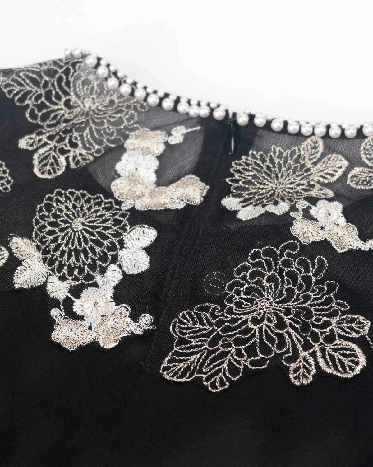 Small bright accents trace the neckline above the floral embroidery.