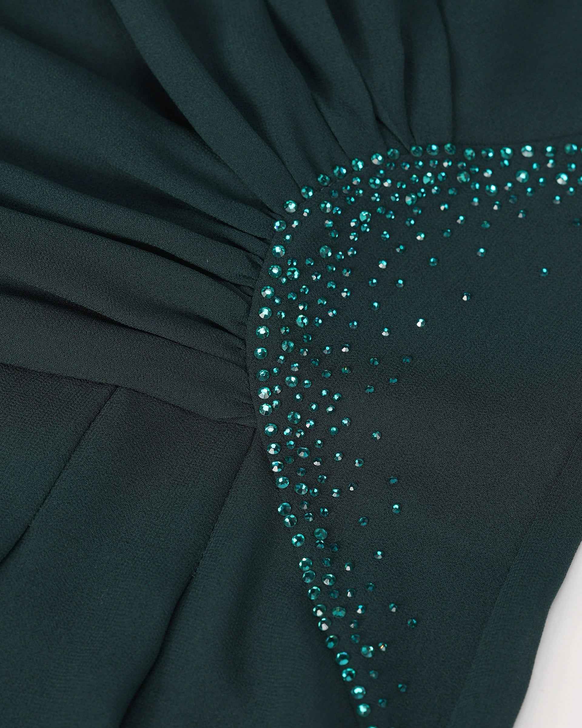 Small reflective accents sit along the gathered waist against deep green fabric.