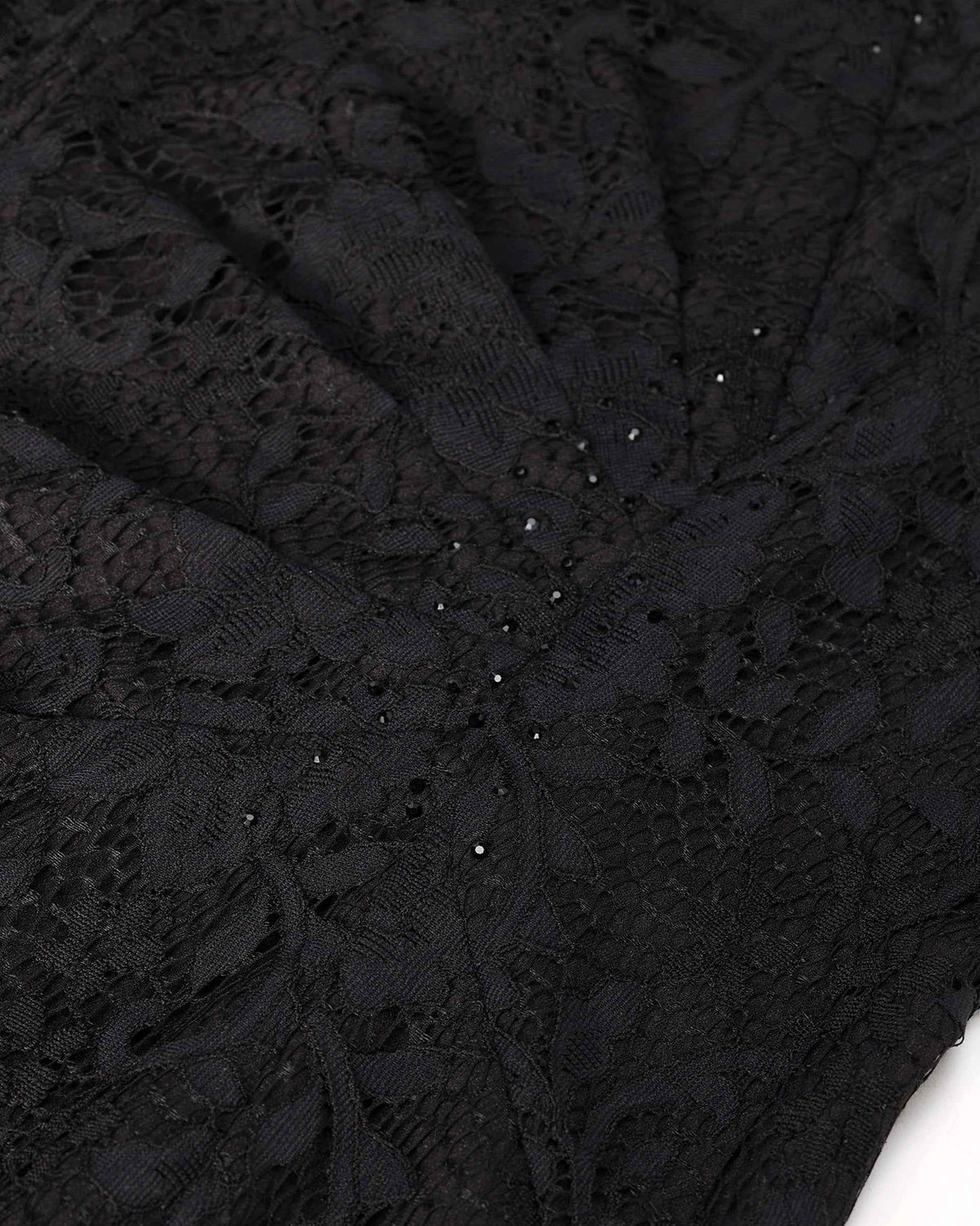 The black lace gathers into folds across the body, bringing its raised floral texture into changing light.
