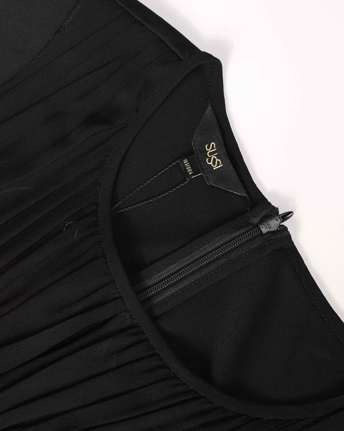 Closely spaced gathers begin beneath the neckline, with a fastening visible at the back.